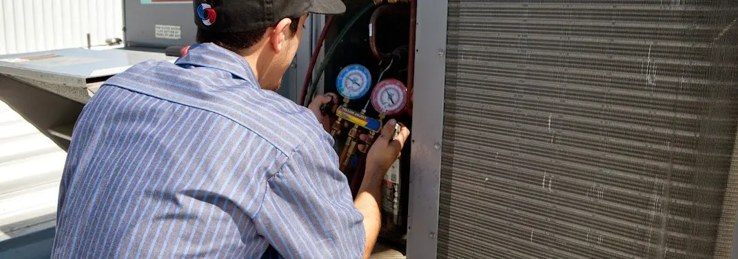 HVAC technician servicing a condenser unit in Hammond
